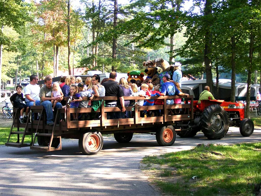 Campers riding a tractor pulled hay wagon through the campground