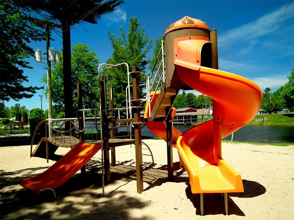 Playground with a yellow spiral slide on sand