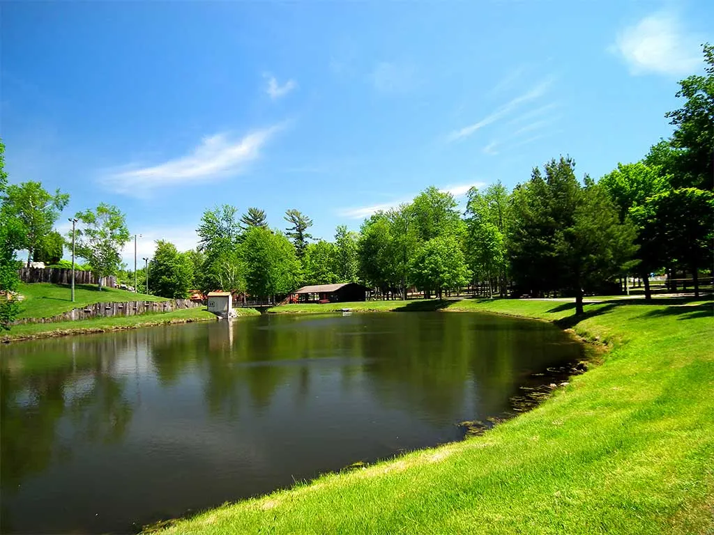 The campground pond surrounded by green lawn and trees