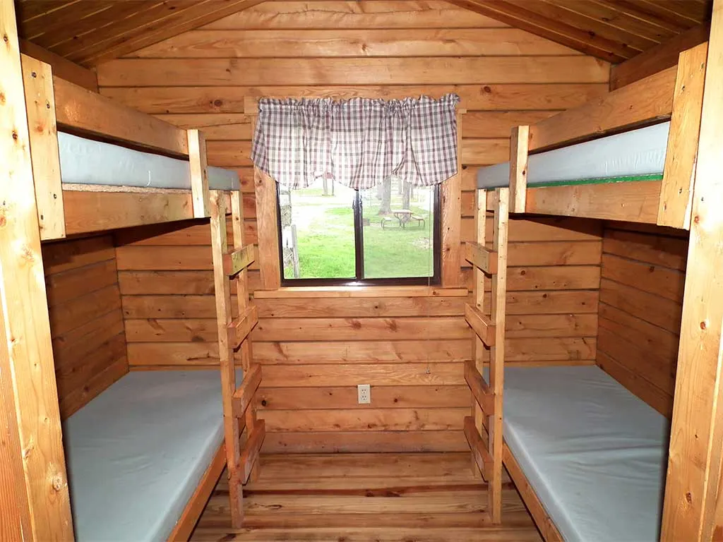 Inside a rustic cabin with two sets of bunk beds